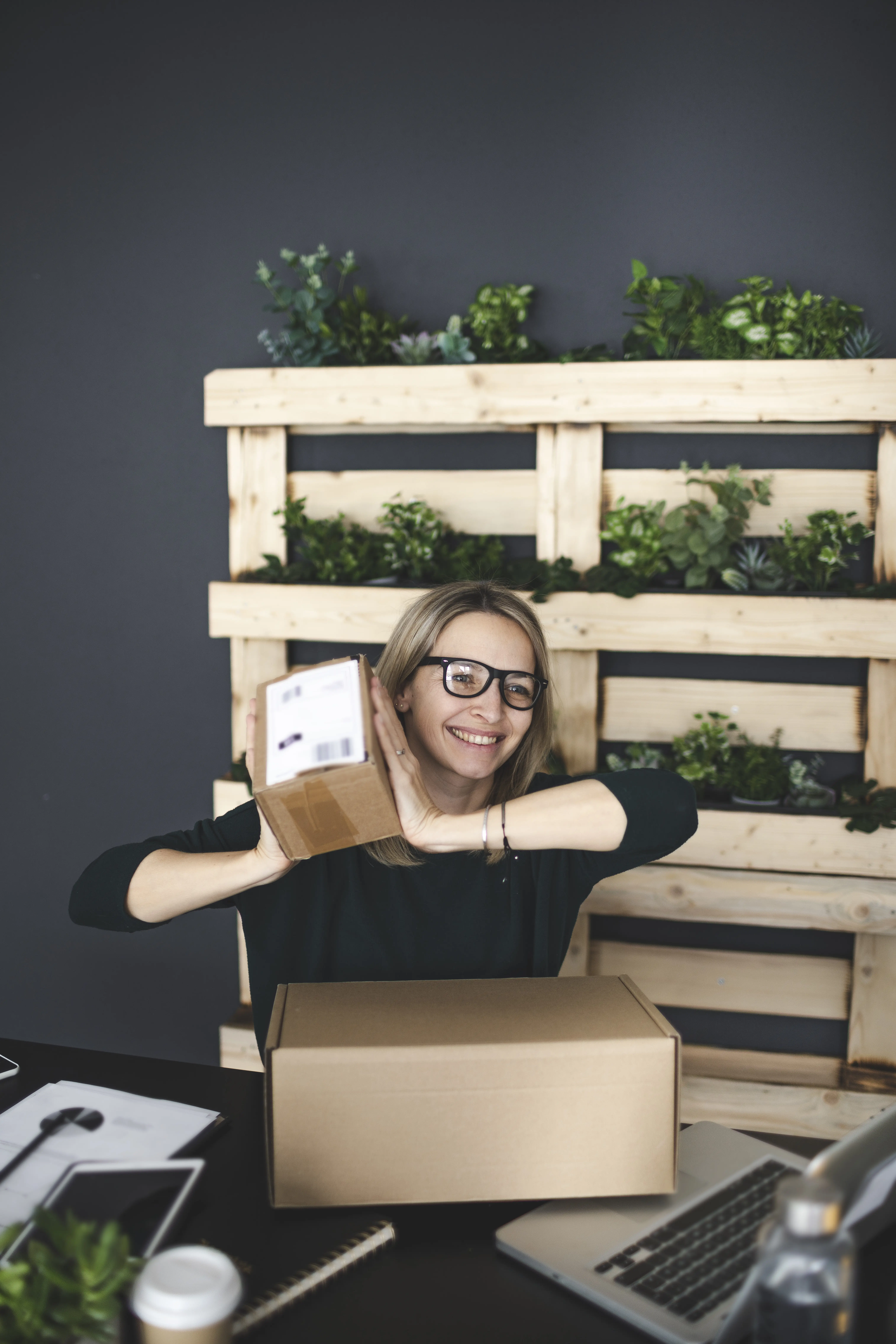 Porträt einer lächelnden jungen Frau, die auf einem Tisch sitzt.